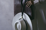 White hat clipped to purse with black hat strap