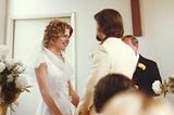A man and a woman at the alter saying their vows in their wedding
