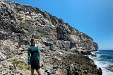 picture of a woman in front of a cliff beside the ocean