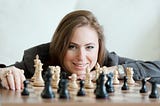 Gm Judit Polgar is posing for a photo with a chess board in front of her.