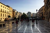 A European plaza with golden evening sun and people walking in shadows