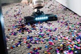 Vacuum cleaning up colourful confetti on a carpet