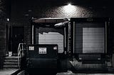 Loading dock and dumpster illuminated by a spotlight.