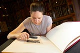 Woman examining old photography using magnifying glass