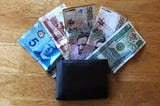 A traveler’s leather wallet containing international dollar bills including Canadian money, Indonesian money, Colombian money