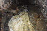 Water rushes over natural bedrock in the Brewery Creek tunnel behind the East Hillside Co-op.