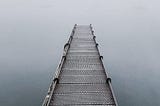 An image of a pier leading into the fog.