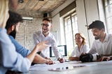 A group of business people sit around, satisified with their employment. How? They followed Acorn Labs extensive of guide on measuring and improving employee satsifaction.