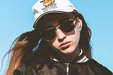 woman in black leather jacket wearing white cap and black sunglasses