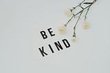 The words “BE KIND” with flowers