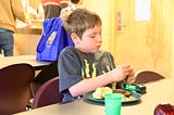 Boy at a shelter eating a meal.