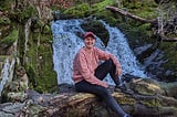 Sophie sat on a tree log in front of Stock Ghyll Force Waterfall