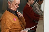 A senior voter examines his ballot before selecting candidates.