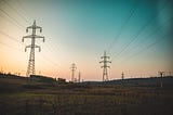 Transmission lines run along towers over a grassy field.