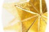 An oval image with gold stars within it, one larger, then behind it, one softer looking