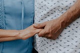 Two elderly people holding hands.