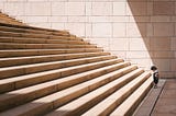 A child waiting at the bottom of very wide steps, getting ready to take the first step.