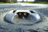Photo of a Catseye set into a road, with the rubber housing and the glass reflectors visible