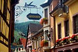 Colorful facades in an alley in Kaysersberg with an old sign showing the name of the town.