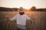 Woman alone in field at sunrise / sunset