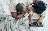 Black father working from home with child on laptop