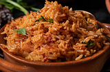 Photo of tomato rice in earthenware bowl.