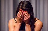 A woman with her hands covering her face.