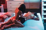 Woman performing a relaxing and sensual massage to a man on the bed