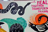 A white canvas displays a variety of hand-painted images including a black and white rendition of the Bono Adinkra symbol and a winding black snake. In white lettering, the snake’s body reads “believe we can,” and pink text by the snake’s head reads “heal together transform trauma.”
