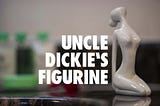 An abstract pale green ceramic of a kneeling nude, just to the right of large white caption saying Uncle Dickie’s Figurine.