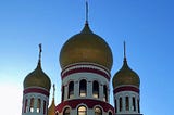 The golden domes of the Holy Virgin Cathedral up against a blue sky.