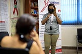A community outreach worker at Viviendo Positivamente demonstrates how to use a condom.
