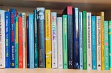 A bookshelf full of books by autistic writers — I’m not up for typing up the full list, sorry! If anyone would be up for doing it for me and sending it over, I’d love that.