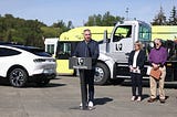 Executive Constantine delivers remarks in front of electric vehicles.