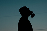 A silhouette of a man in a gas mask against a dusk sky