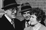 File: Telly Savalas, Dan Frazer, Jean LeBouvier, Kojak 1975.JPG by CBS Television. The photo has no copyright markings. This work is in the public domain in the United States because it was published in the United States between 1928 and 1977, inclusive, without a copyright notice.