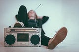 woman laying on bed with grey radio