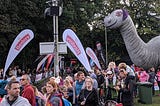 The finish line and crowds next to the finish line of the Loch Ness Marathon with a giant model of the Loch Ness Monster