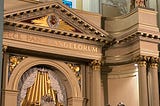 Interior image of altar in St. Louis Cathedral — statues are set up on top of the altar and a statue of St. Peter holds the key to heaven, on a ledge on the right side. There are the words “Ecce Pano Angelorum” written on the altar, “Behold the bread of angels.”