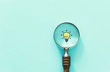 Magnifying glass viewing an illustration of a light bulb.
