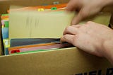 View of hands removing a paper file from a box of files