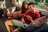 Two people on a couch buying something on a laptop.