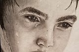 Pencil drawing of a nine-year-old boy’s face. The boy has wet hair and water droplets trickling down his face like he just came in from the ocean or is perhaps sweating