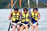 Mother and sons having a paragliding adventure together while unschooling.