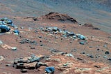False colour view of rocks on the martian surface. The foreground rocks have a bluish tone to them, while the surrounding dirt and background rocks are more brown/orange.