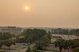 A photo captures the wildfire haze covering an area of Greenbelt, Maryland, with buildings in the forefront. The background of the image is difficult to make out due to the haze.