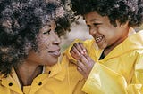 Photo of a woman and a child wearing yellow raincoats. Symbolizes a mother and daugher, raincoats symbolise self care to stop yourself from drowning.