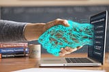A human hand shaking a glowing cyan digital mesh hand emerging from a laptop screen, symbolizing how developers can build AI agents locally using open-source tools instead of expensive APIs.