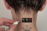 Hand placing aux lead into sockets on back of female model’s neck