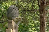 Crumbling old concrete statue of Humpty Dumpty, the egg that sat on the wall from the nursery rhyme. Humpty Dumpty in this photo taken in a nearby park is cracked and falling to pieces without even falling yet.